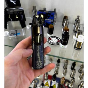 OXVA NeXLIM Pod Kit 1500 мАч — Под-система середніх розмірів з кольоровим дисплеєм реальне фото в руці від ELIQ на фоні витрини